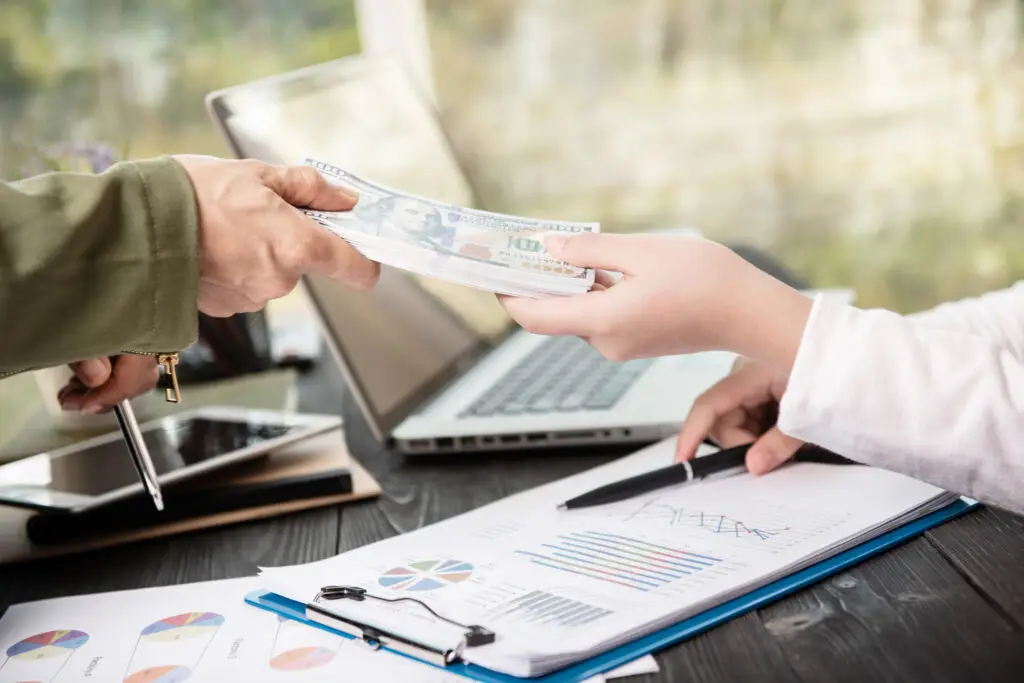 Businessman handing money to his partner while signing a contract